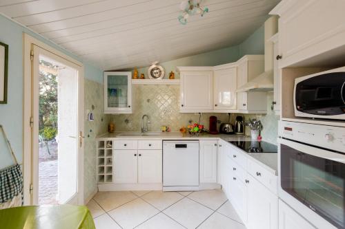 une cuisine blanche avec des armoires blanches et une fenêtre dans l'établissement Villa Carole YourHostHelper., à Roquebrune-sur Argens