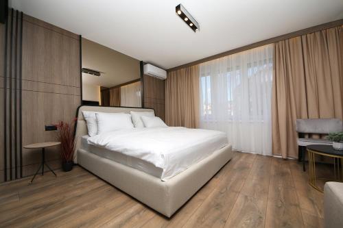 Un dormitorio con una gran cama blanca y una mesa en Nest Apartments Sarajevo en Sarajevo