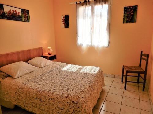 a bedroom with a bed and a window and a chair at La Balme in Loubressac