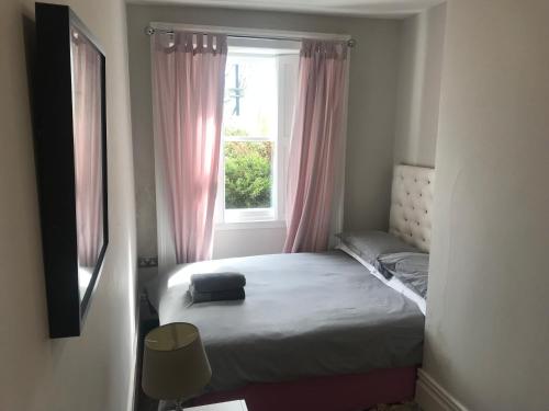 a small bedroom with a bed with a window at Collingwood House Tynemouth in Tynemouth