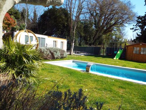 a swimming pool in a yard with a playground at La Maison du Moulin de Tartay in Avignon