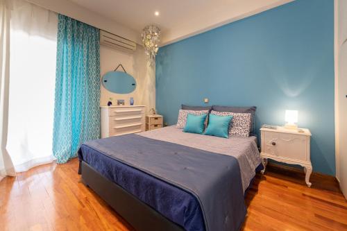 Schlafzimmer mit blauen Wänden und einem Bett mit blauen Kissen in der Unterkunft Vintage Boutique Penthouse in Piräus
