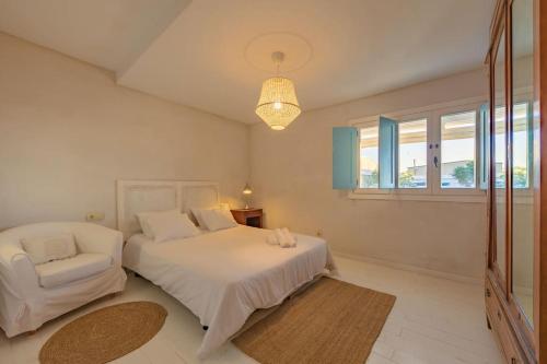 - une chambre avec un lit blanc et une chaise dans l'établissement Casa Rural La Vega 1 en Tarifa, à Tarifa