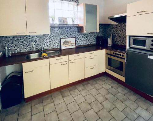 a kitchen with white cabinets and a sink and a stove at Ferienwohnung Rosenauer in Purbach am Neusiedlersee