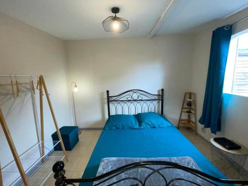 1 dormitorio con cama con sábanas azules y ventana en Ti Caz de Ness, en Saint-Leu
