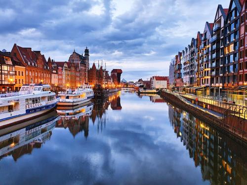 a river with boats in a city with buildings at Apartament enjoy! Gdańsk Old Town in Gdańsk