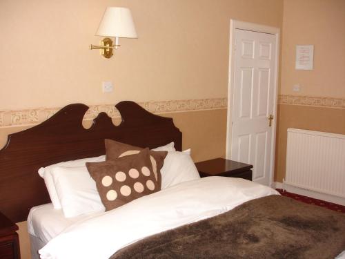 a bedroom with a bed with white sheets and a lamp at The Park Hotel in Dunoon