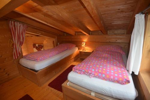 two beds in a cabin with wooden walls at Feriendorf Tauerngast in Hohentauern