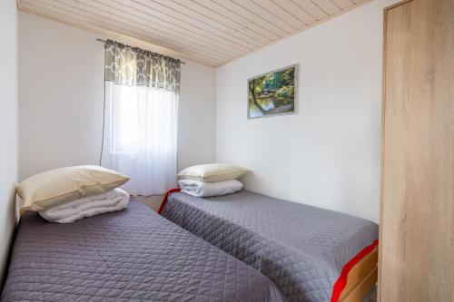 two twin beds in a room with a window at Domki w Zawozie nad Soliną in Zawóz