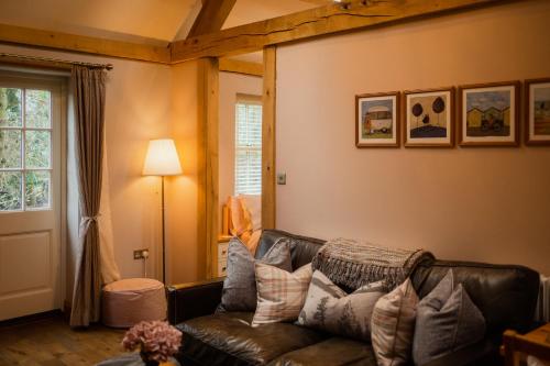 a living room with a leather couch and a window at White House Barn, near Yarm / Stockton-on-Tees in Yarm