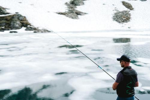 a man standing in the snow holding a fishing rod at Chandolin Boutique Hotel in Chandolin