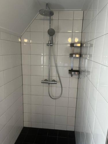 a white tiled shower with a shower head at Veendijkhoeve in Oosterwolde