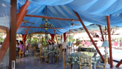 un grupo de mesas y sillas bajo una tienda azul en Jungle Moon Homestay จังเกิ้ลมูน โฮมสเตย์ บางเสร่, en Sattahip