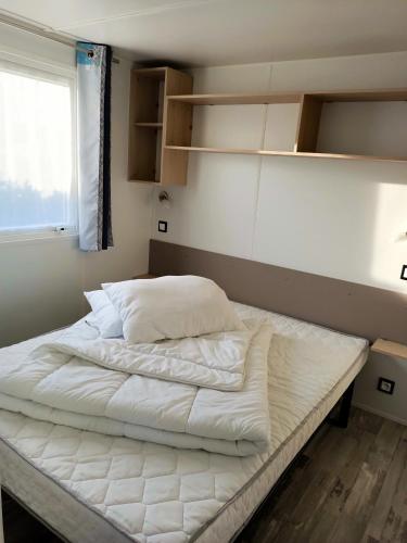 une chambre avec un lit avec des draps blancs et une fenêtre dans l'établissement Bungalow charmant à Onzain avec piscine partagée, à Onzain