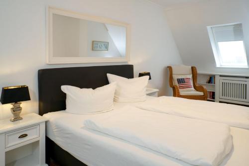 1 Schlafzimmer mit 2 weißen Betten und einem Stuhl in der Unterkunft Haus Strandburg, Wohnung17, 25980 Westerland in Westerland