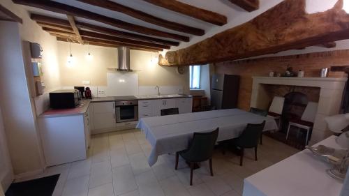 a large kitchen with a table and a fireplace at Gîte Saumurois 7 personnes in Montreuil-Bellay