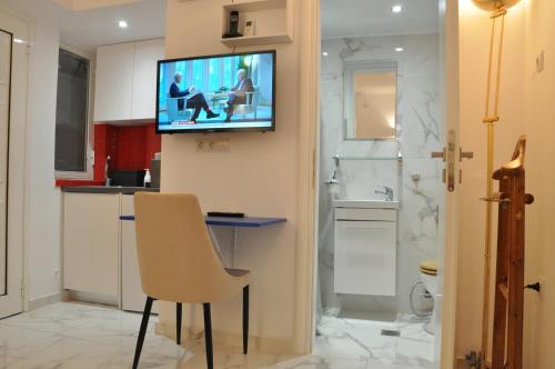 uma casa de banho com uma televisão numa parede com uma cadeira em Taratsaki em Atenas