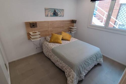 um quarto com uma cama com almofadas amarelas e uma janela em Nuevo apartamento en la playa de Castelldefels! em Castelldefels