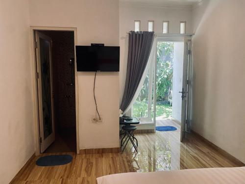 1 dormitorio con 1 cama y TV en la pared en Umah Putih, en Nusa Penida