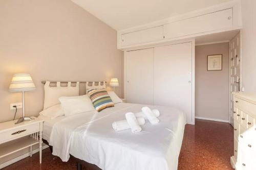 um quarto branco com uma grande cama branca e 2 almofadas em Apartment Muralla em Vilassar de Mar