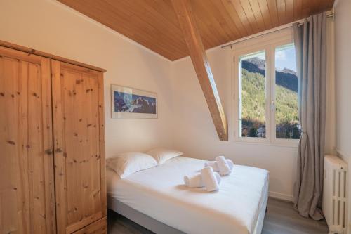um quarto com uma cama com lençóis brancos e uma janela em Résidence Majestic em Chamonix-Mont-Blanc