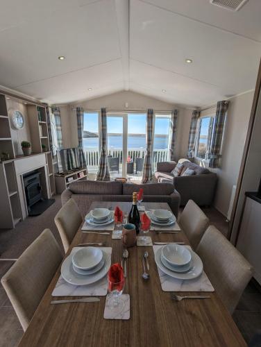 a dining room with a table and a living room at LOCATION LOCATION Beautiful Modern Frontline Caravan Haven Littlesea Weymouth in Weymouth
