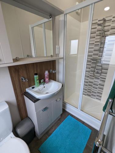 a bathroom with a sink and a shower at LOCATION LOCATION Beautiful Modern Frontline Caravan Haven Littlesea Weymouth in Weymouth