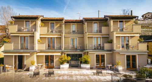 an apartment building with tables and chairs in front of it at Réva Residences and Pool in Monforte dʼAlba