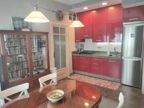 eine Küche mit roten Schränken und einem Holztisch in der Unterkunft Vive Triana in Sevilla