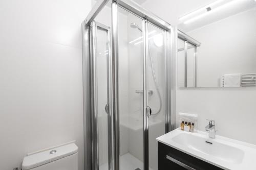 ein weißes Bad mit einer Dusche und einem Waschbecken in der Unterkunft Résidence Sommets in Chamonix-Mont-Blanc