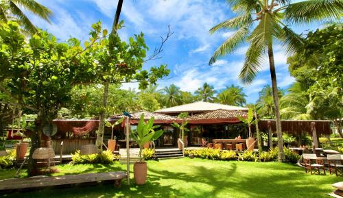 a resort with palm trees and a grass yard at Aldeia do Mar Sensorial Hotel in Itacaré