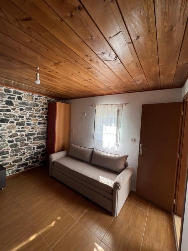 Mountain House في Gáïa: أريكة في غرفة مع جدار من الطوب