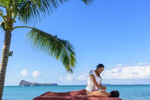 a man laying on the beach with a woman at Myra Seafront Suites with LOV in Cap Malheureux