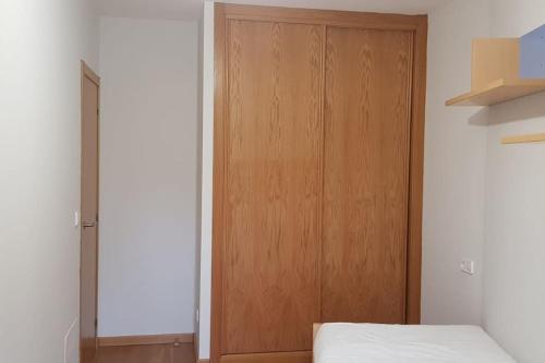 ein Schlafzimmer mit einer Holztür neben einem Bett in der Unterkunft Maravilloso apartamento en Villagarcia de Arosa in Vilagarcia de Arousa