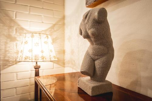 a statue of a dog sitting on a table next to a lamp at Réva Residences and Pool in Monforte dʼAlba