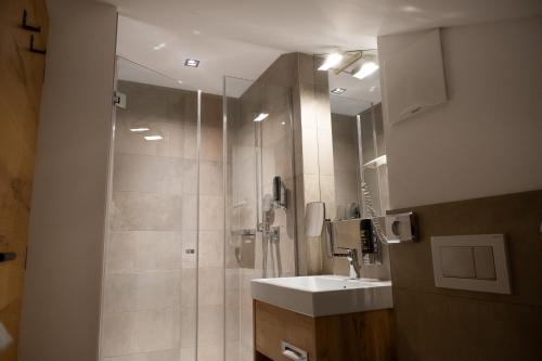 y baño con ducha, lavabo y espejo. en Hotel Sendlhof en Waidring