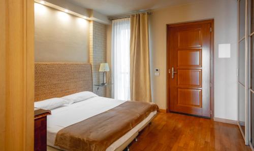 a bedroom with a bed and a wooden door at Réva Residences and Pool in Monforte dʼAlba