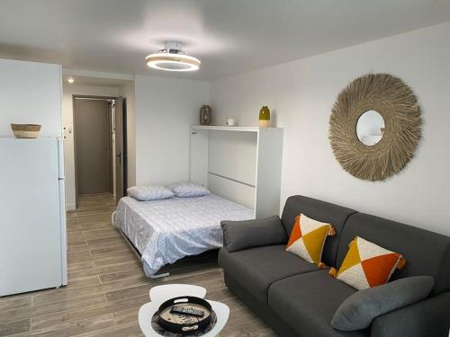 un salon avec un canapé et un lit dans l'établissement Studio rénové 200 m de la plage avec parking privé, au Cap d'Agde