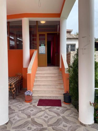a staircase leading to a house with an orange door at Hotel Bar Restaurant Mete in Peshkëpi