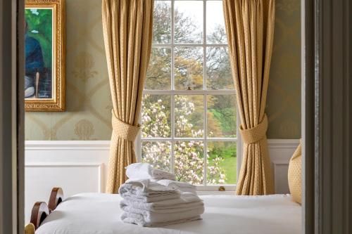 a bedroom with a window with towels on a bed at Plas Dinas Country House in Caernarfon