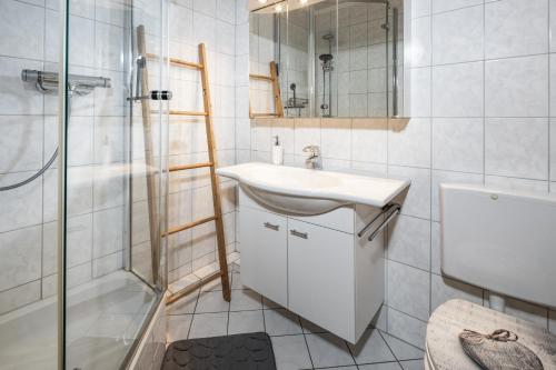 a white bathroom with a sink and a shower at FeWo Berkristall mit Hallenbad in Berchtesgaden