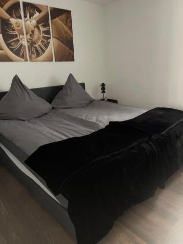 a bed with a black blanket on top of it at Propeller Gästehaus OG in Eppingen