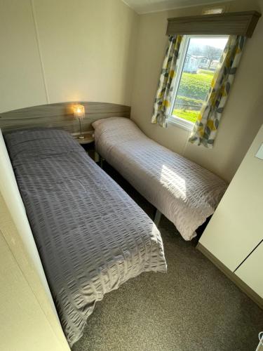 two beds in a small room with a window at Atlas By The Sea - Craig Tara, Ayr in Ayr