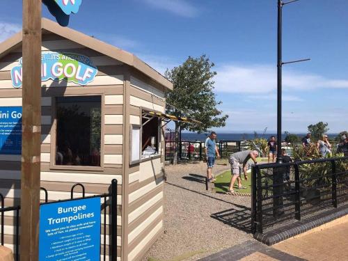 a small building with people standing outside of it at Atlas By The Sea - Craig Tara, Ayr in Ayr