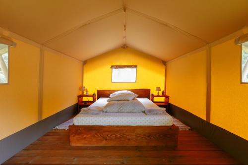 a bed in a room with yellow walls at Green Camp - Adventure Glamping in Gura Teghii