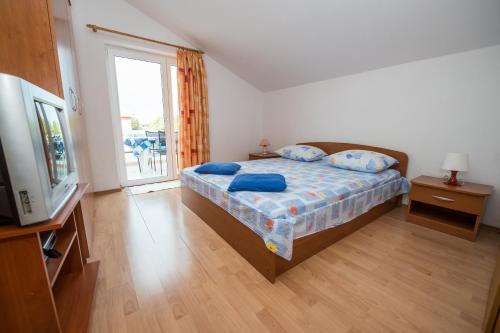 a bedroom with a bed and a tv and a window at Apartmani Lory in Tribunj