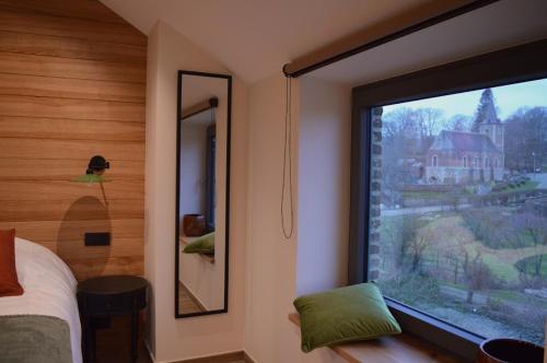 a bedroom with a window with a view of a church at La Jardinière in Érezée