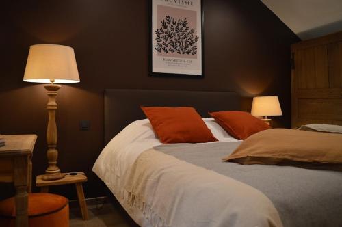 a bedroom with a bed with orange pillows and a lamp at La Jardinière in Érezée