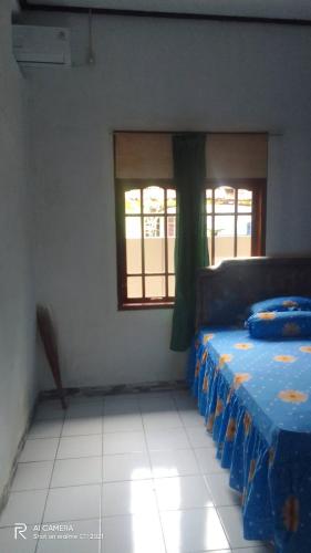 ein Schlafzimmer mit einem Bett mit einer blauen Decke und einem Fenster in der Unterkunft Homestay H mamun in Cilowa