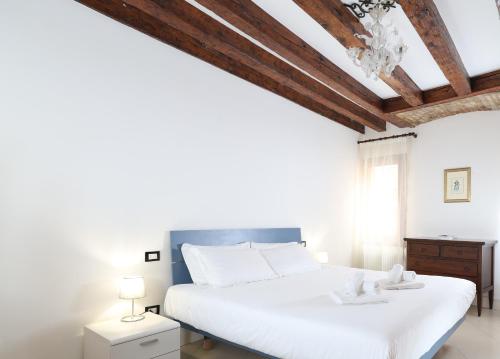 a bedroom with a large white bed with a wooden ceiling at Bricola Biennale Apartments in Venice